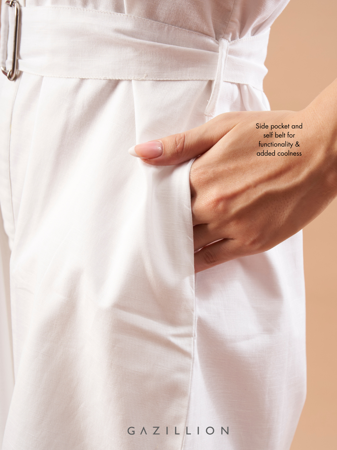 White outfit with side pocket and waist belt on a beige background.