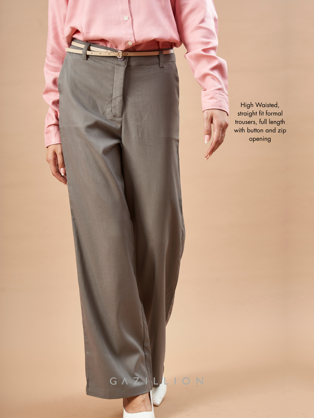 Person wearing a pink shirt and gray formal trousers on a beige background