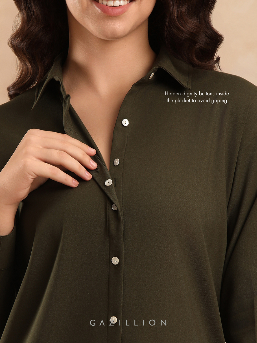 Woman wearing a dark green shirt with hidden dignity buttons, on a beige background.