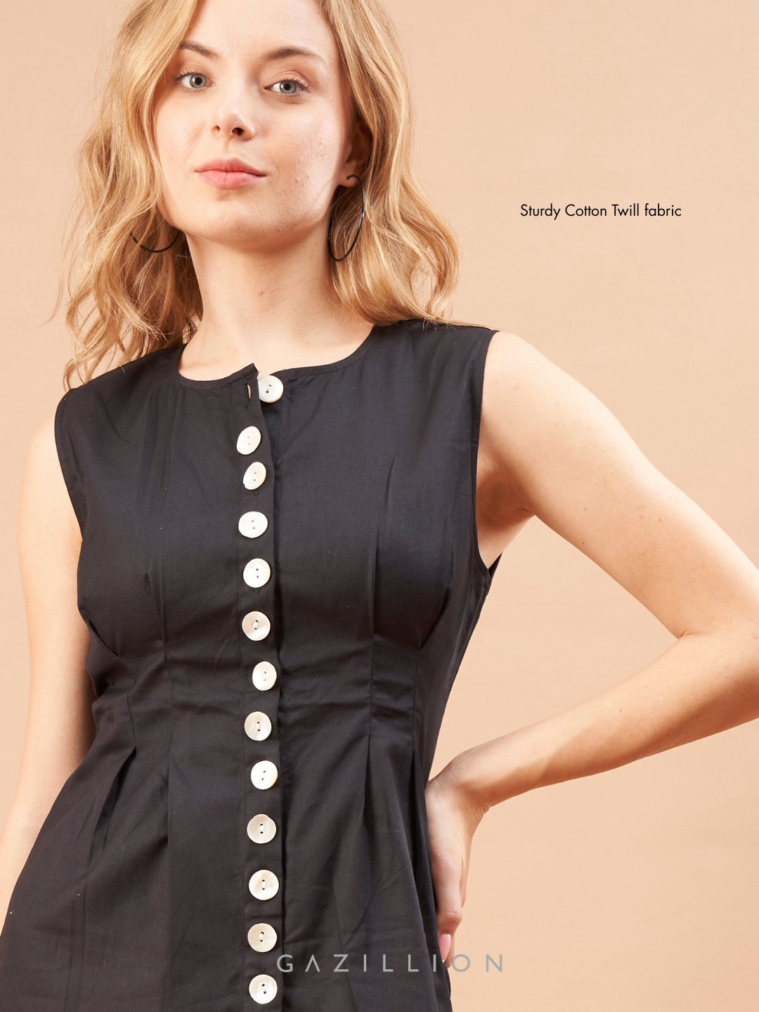 Woman wearing a black sleeveless dress with buttons on a beige background