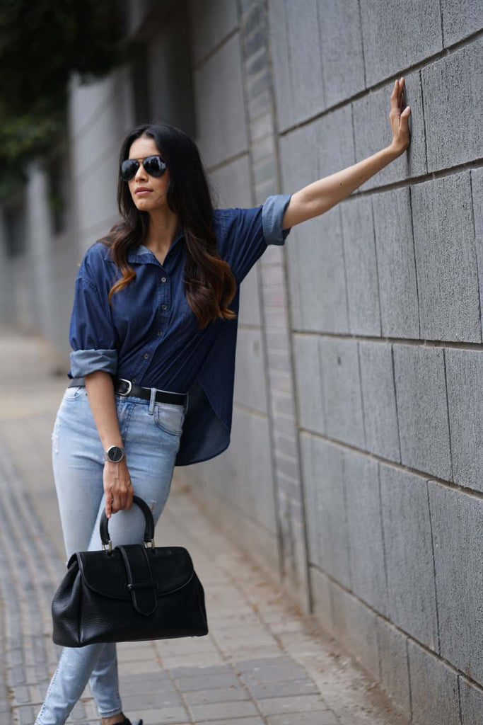 A woman styled beautifully in a Gazillion Oversized Blue Denim Shirt teamed with a skinny denim and a smart formal black bag