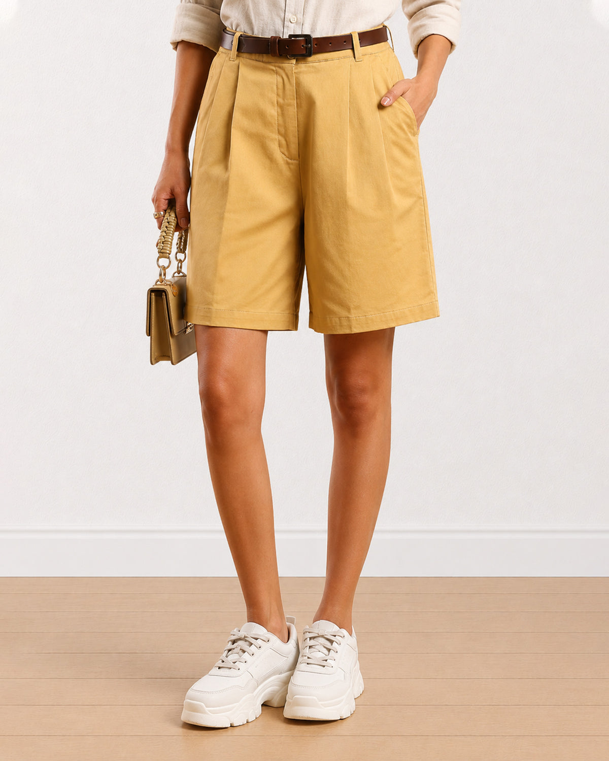 Close-up of Celine camel beige shorts showing front pleats and knee length hem