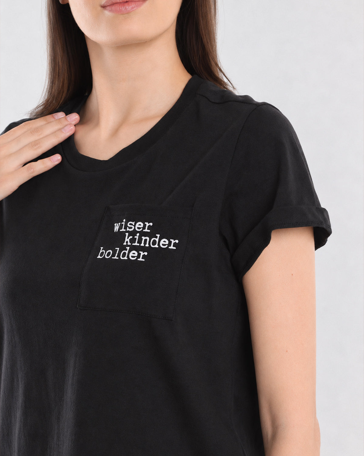 Close-up of Christiana black t-shirt chest pocket with Wiser Kinder Bolder print