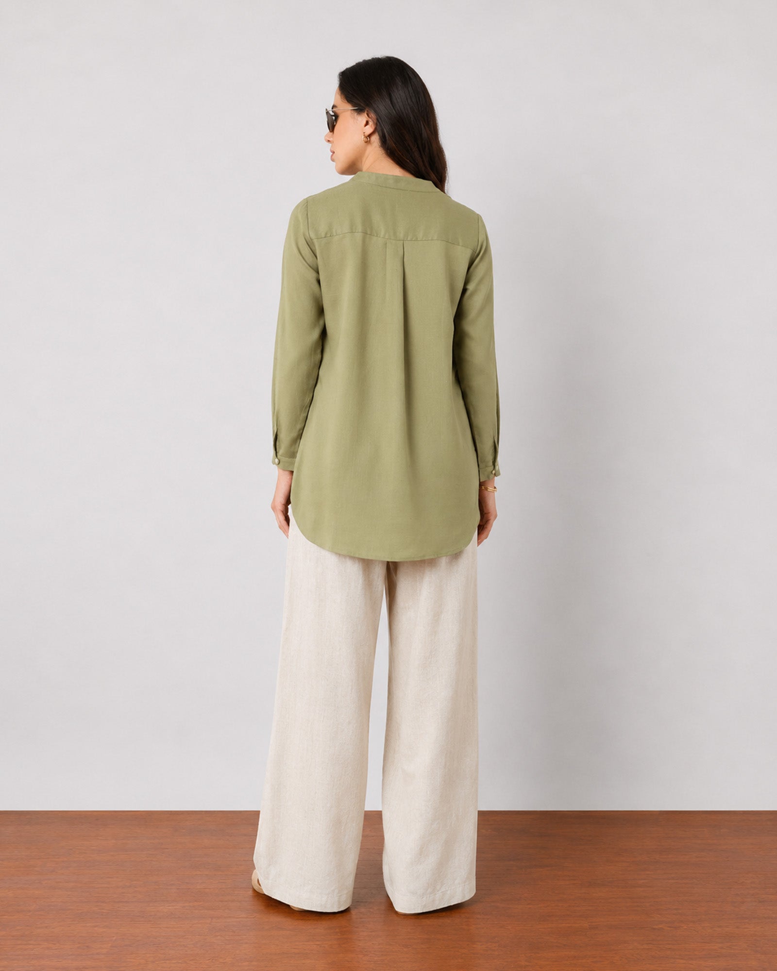 Gemini moss green linen tunic top, back view showing the yoke pleat and curved hem