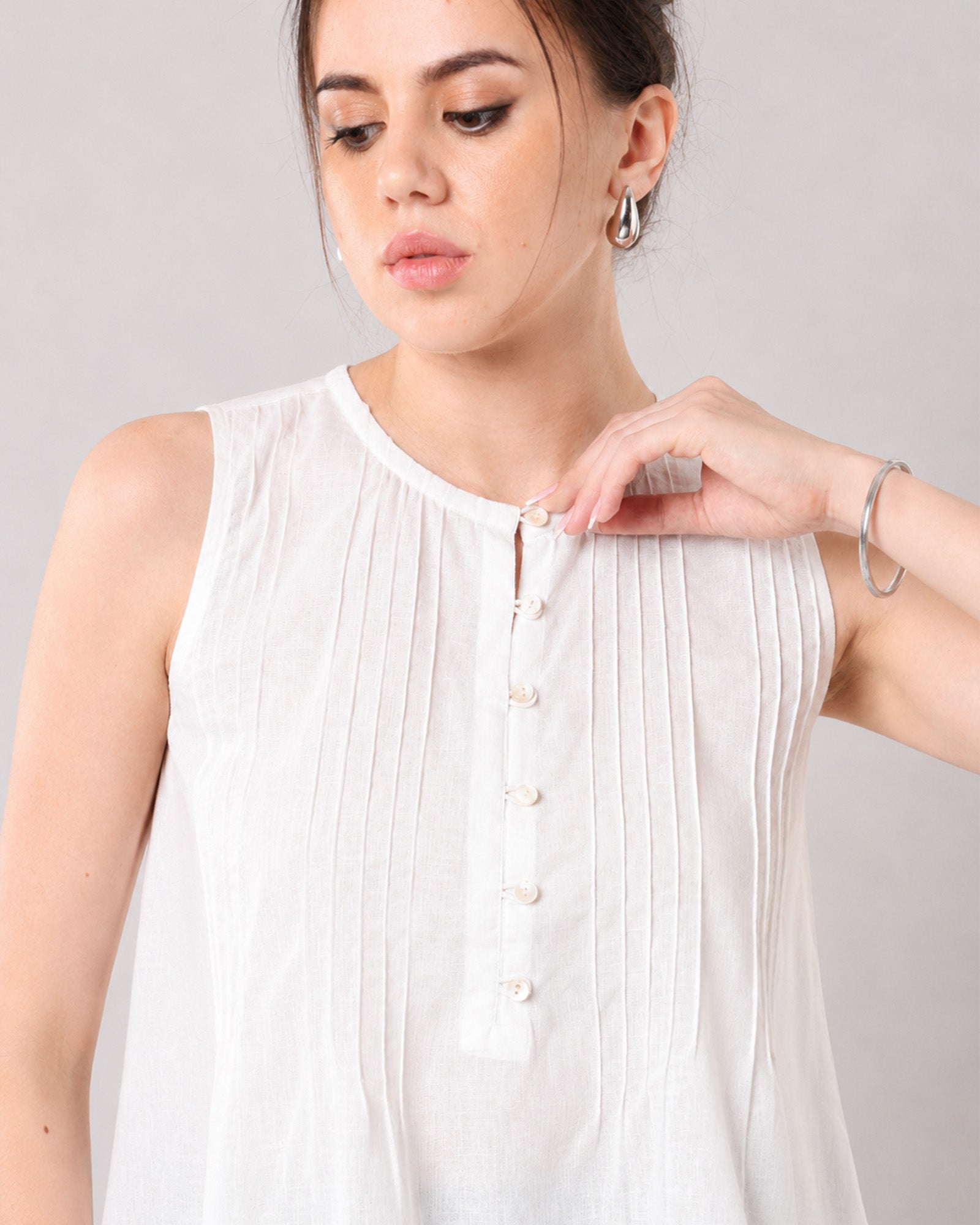 Close-up of Gill white linen top Henley neckline, button placket and fine pin tuck pleats
