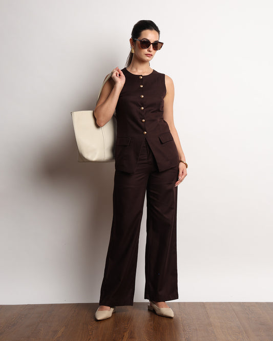 Harriet brown vest with golden buttons styled with matching trousers and a cream handbag, full-length view