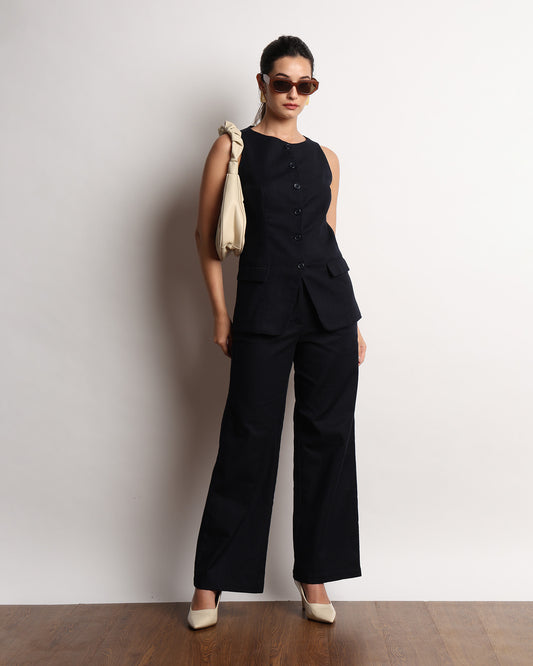 Henrid navy sleeveless vest top styled with matching wide-leg trousers and a black handbag, full-length angled view