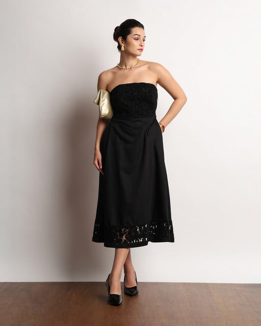 Here black lace strapless dress worn with hands on the hips, front view