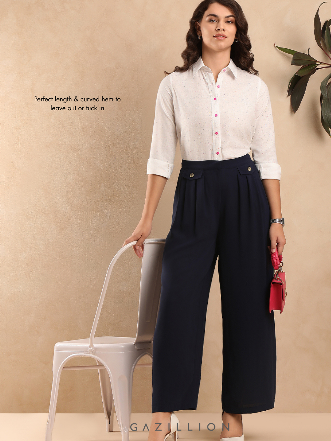 Woman wearing a white shirt and navy pants against a beige background