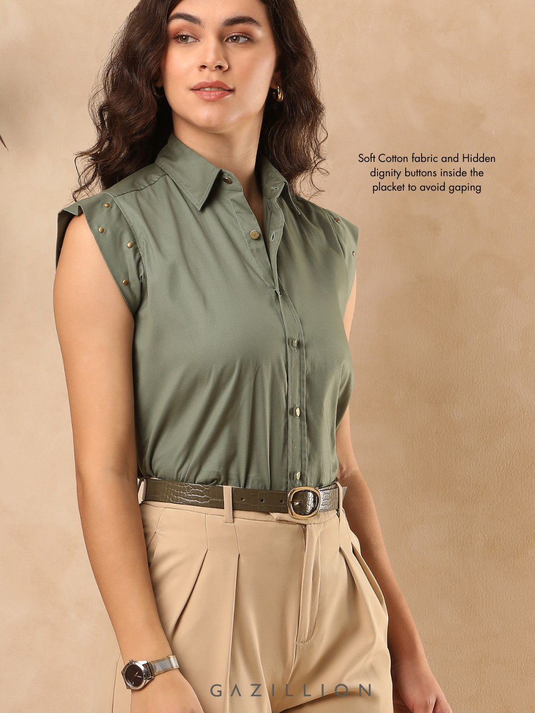 Woman wearing a green sleeveless shirt with buttons and beige pants on a beige background