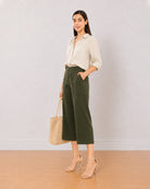 Bella olive green 3/4th straight pants front view with a hand in the side cross pocket