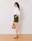 Bobby olive green medium waist shorts side view with a hand in the side pocket