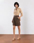 Camila olive green city shorts front view, loose fit with hand in the side cross pocket