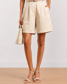 Close-up of Celine beige poly cotton shorts showing front pleats and side cross pocket