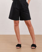 Close-up of Celine black knee length shorts showing front pleats and knee length hem