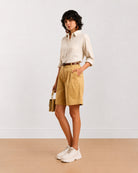 Celine camel beige shorts front view with hand in side cross pocket and knee length