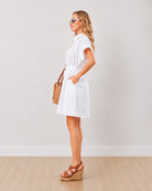 Daisy white 100% cotton shirt dress with a belted waist and straight fall, side profile view