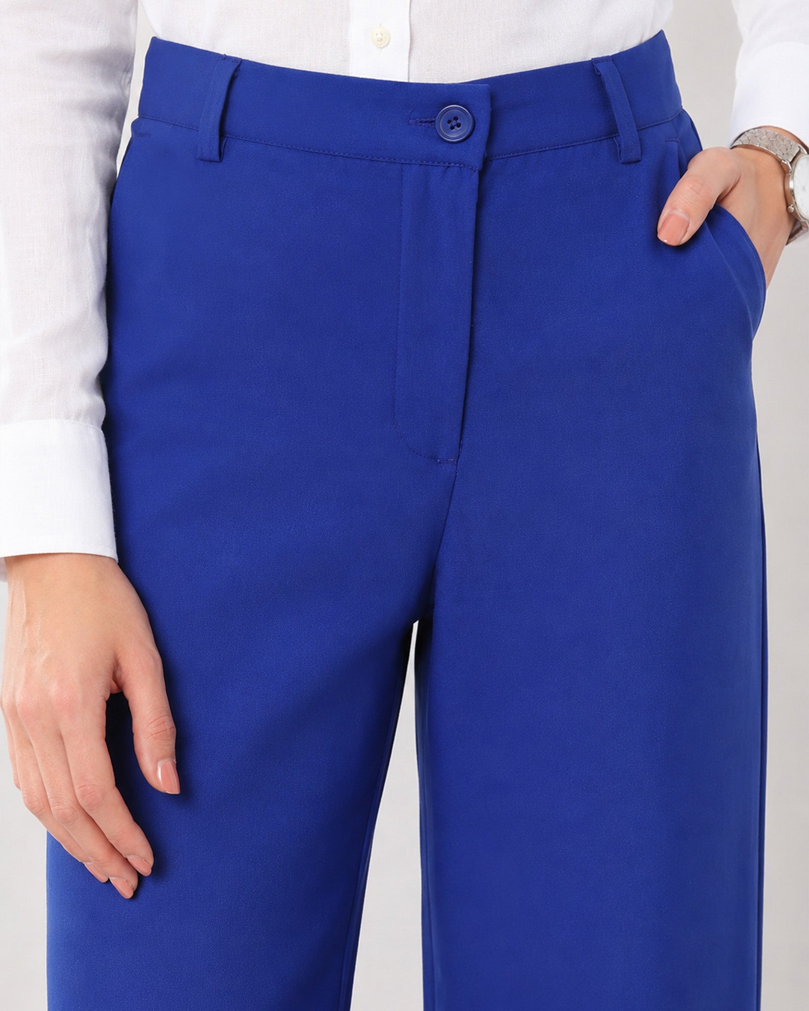 Close-up of Glin royal blue cotton pants waistband, belt loops, button fly and structured front pleat