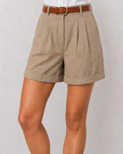 Goldy muddy brown linen shorts with a neat cuffed hem, cropped waist-down view