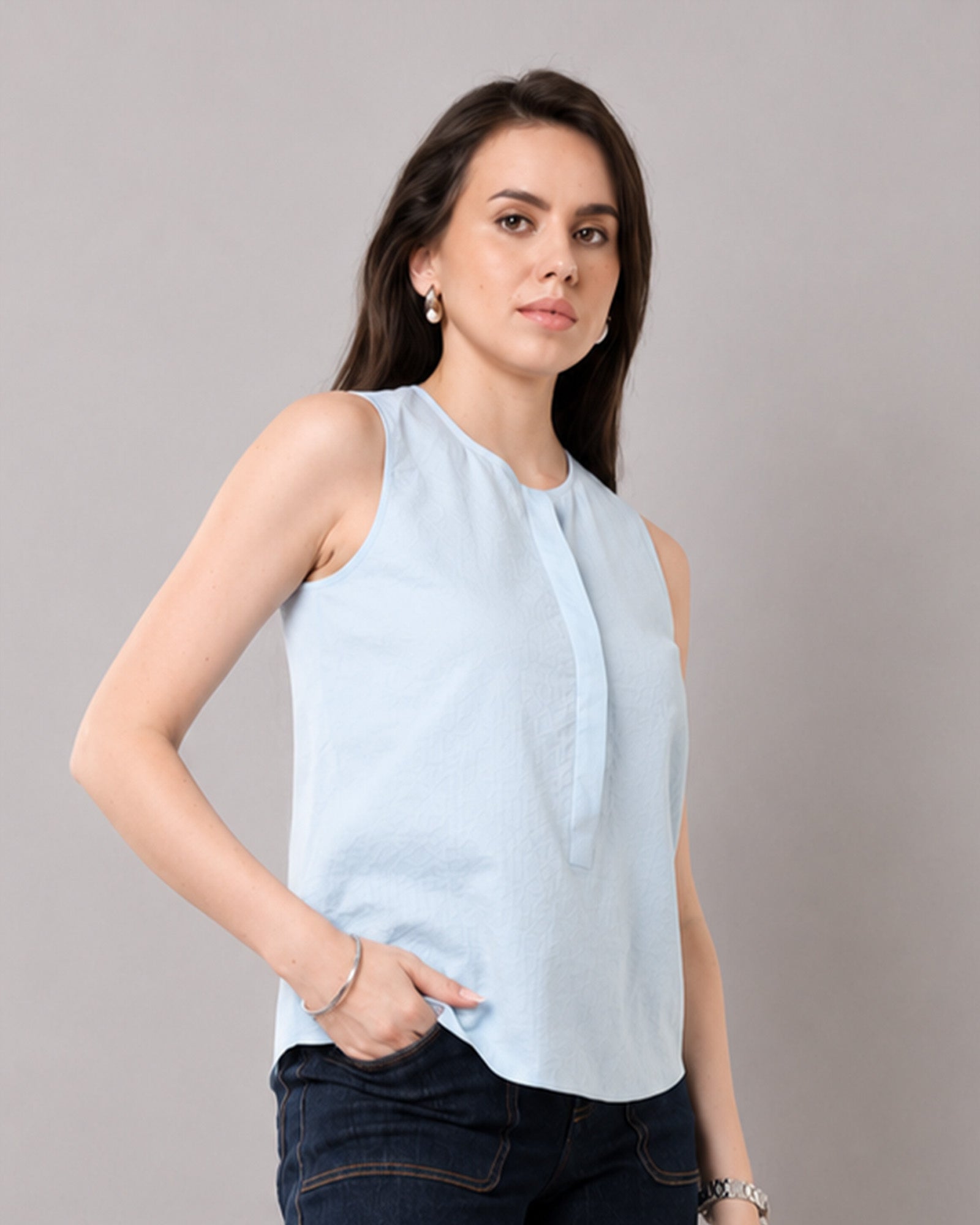 Gusta sky blue sleeveless cotton top with a relaxed fit and curved hem, waist-up view