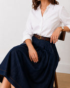 Hansel indigo blue denim skirt, seated view showing soft cotton pleat drape and high waist