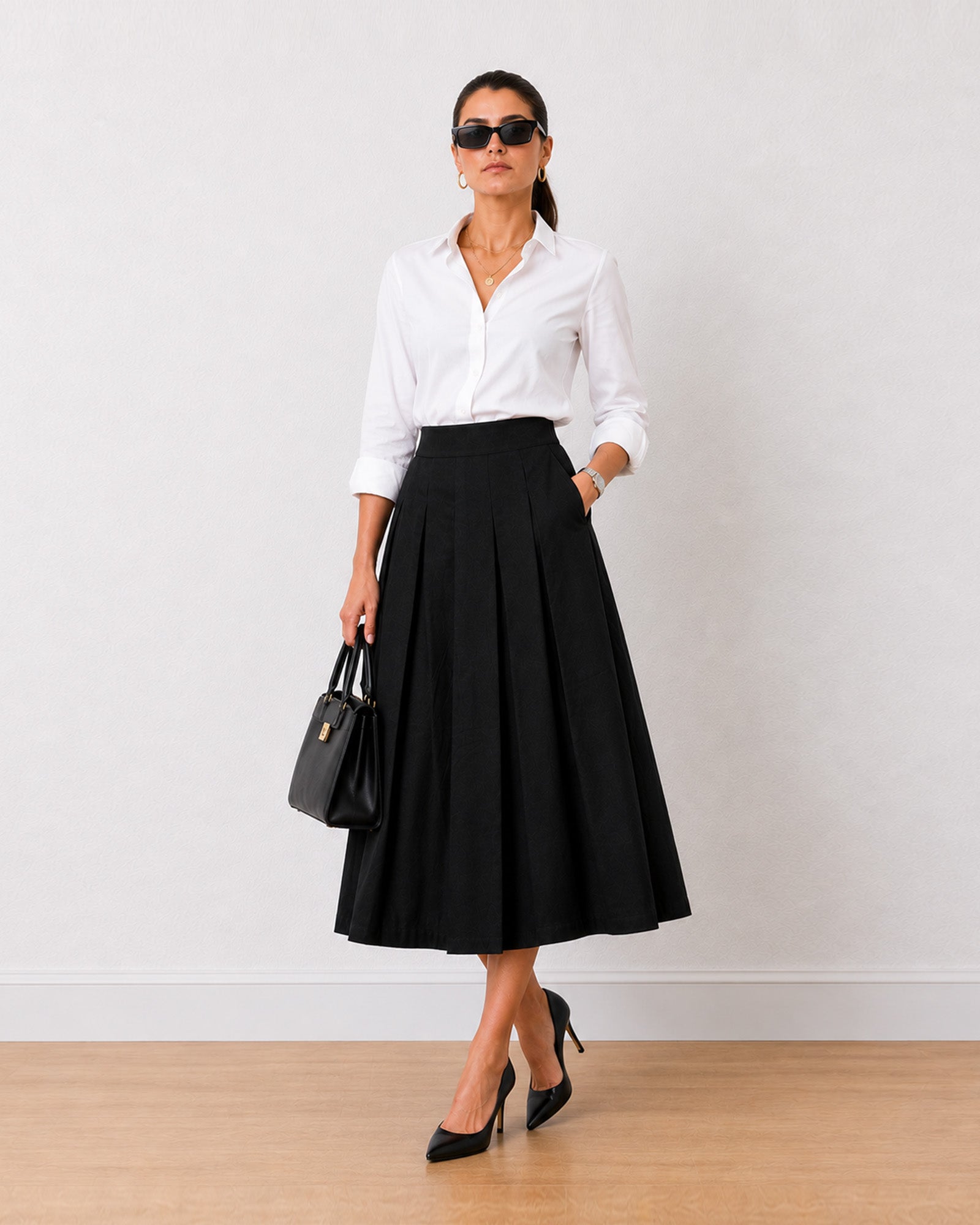 Hester black cotton pleated skirt, front view showing flared midi silhouette
