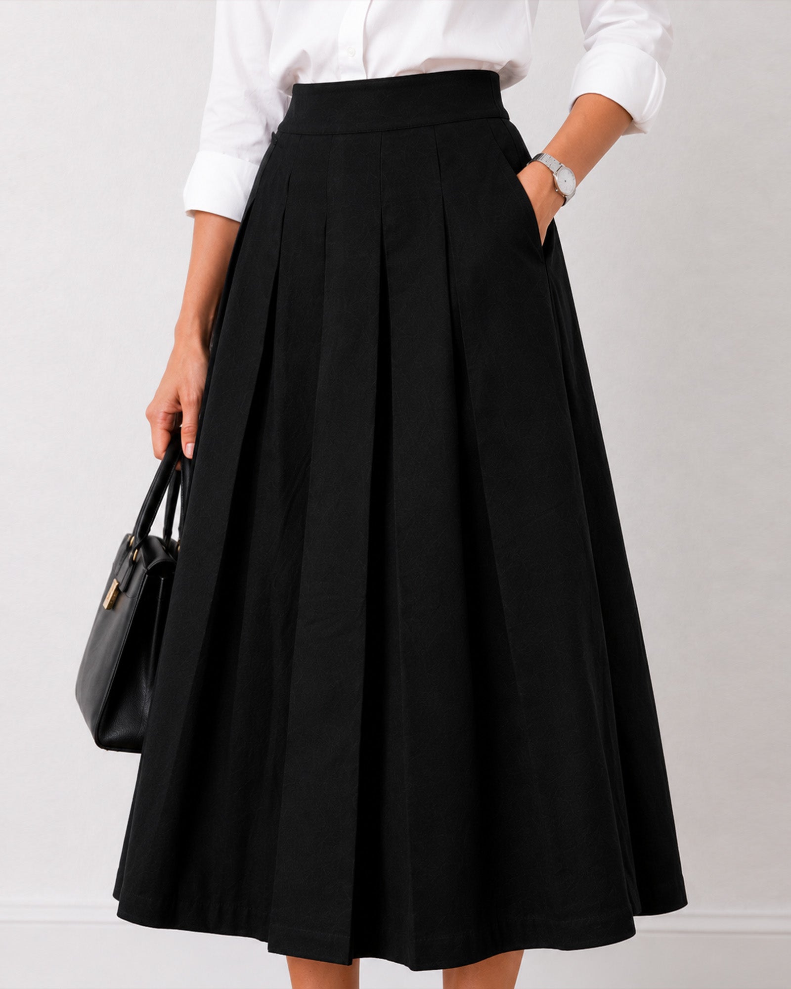 Close-up of Hester black cotton midi skirt showing front pleats and side pocket